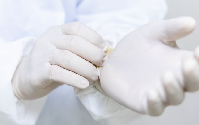 Close-up of hands putting on large nitrile gloves.