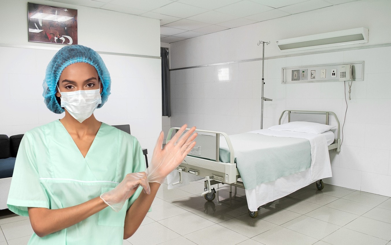 Nurse putting on sterile gloves in hospital room.