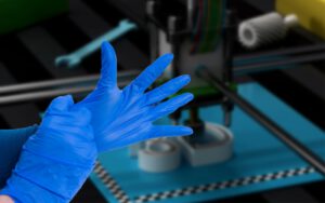 Hands putting on blue nitrile gloves for resin 3D printing.