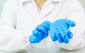 Close-up of hands putting on blue nitrile gloves.