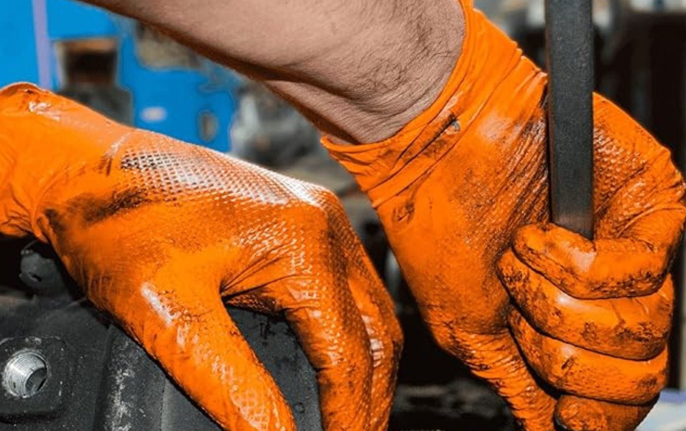 Close-up of heavily soiled orange nitrile gloves during use.