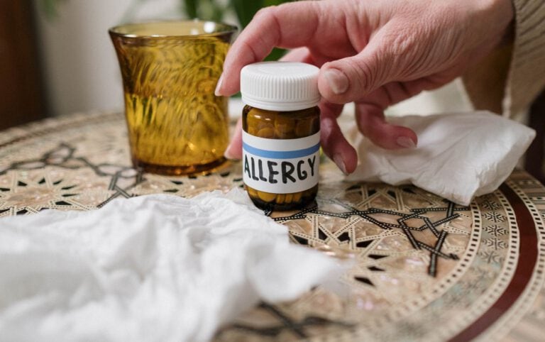 Close-up of hand holding allergy medication bottle labeled "ALLERGY".