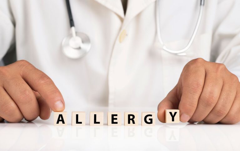 Doctor's hands arranging letter blocks spelling "ALLERGY".