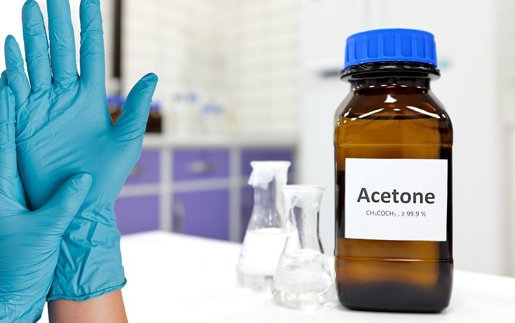 Acetone bottle and nitrile gloves; chemical permeation test.