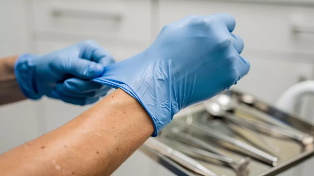 Dental professional properly putting on nitrile gloves